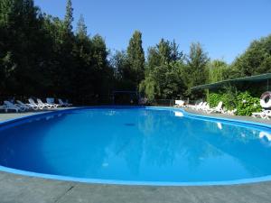 uma grande piscina azul com cadeiras e árvores em Cabañas Parque Salto del Laja em El Manzano