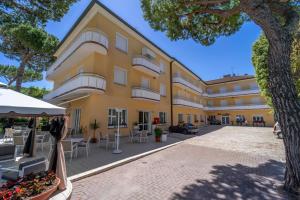 a large yellow building with tables and chairs in front of it at Hotel Romagna in Riccione
