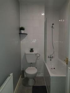a white bathroom with a toilet and a bath tub at London. Gorgeous 2 bed flat near Olympic Park. in London