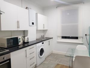 a white kitchen with a washing machine in it at London. Gorgeous 2 bed flat near Olympic Park. in London