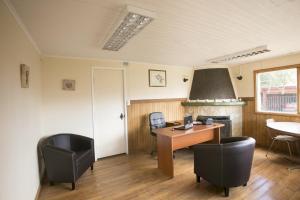 un bureau avec un bureau, une table et des chaises dans l'établissement Rumbo Sur Apart Hotel, à Coyhaique