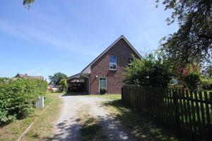 a brick house with a fence next to a dirt road at Ferienwohnung Frida in Althagen