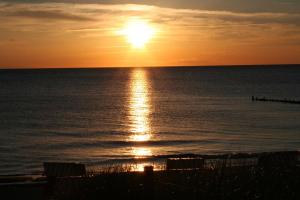 a sunset over the ocean with the sun setting at Ferienwohnung Frida in Althagen