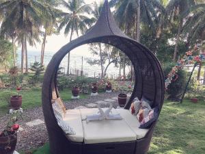 GEM Crystal Water Resort في مدينة دافاو: كرسي أرجوحة الخوص في ساحة مع المحيط