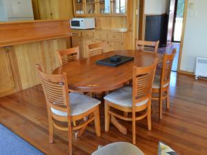 a wooden table and chairs with a laptop on it at Freycinet Sands in Coles Bay