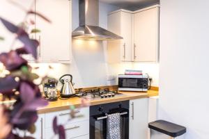 a kitchen with a stove and a microwave at Luxury Modern 3 Bedroom Apartment in City Centre in Edinburgh