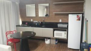 a kitchen with a sink and a refrigerator and a table at Ramada Flat in Recife