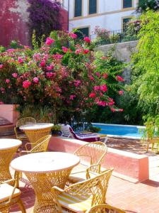 un patio al aire libre con mesas, sillas y flores rosas en Navila Palmera en Ibiza