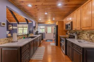 a large kitchen with wooden ceilings and wooden cabinets at Creekside Cabin at Linville Land Harbor in Newland