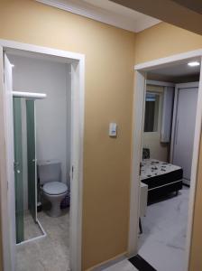 a bathroom with a toilet and a room with a bed at CASA COM PISCINA À BEIRA MAR. in Recife