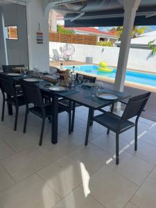 een eetkamer met een tafel en stoelen en een zwembad bij NOUVEAU Villa Ricololo Piscine Balnéo Golf Yoga in Saint-François