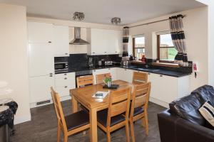 cocina y comedor con mesa de madera y sillas en 1 Eden at Williamscraig Holiday Cottages, en Linlithgow