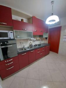 una cocina con armarios rojos y fregadero en Domus Dejanas Selargius, en Selargius