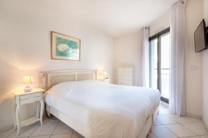 Agence des Résidences - Plein centre de Cannes في كان: غرفة نوم بيضاء مع سرير كبير ونافذة