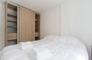 Un dormitorio con una cama blanca con toallas. en Gray Fox Apartments Alem en Ushuaia