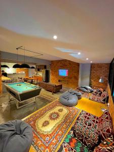 a living room with a pool table and a room with a rug at Arch Dormitorio Cenang in Pantai Cenang