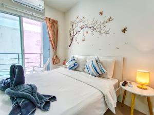 a bedroom with a white bed with a window and a table at Sailor Hotel Pattaya in Pattaya South