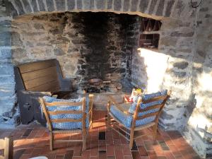 eine Terrasse mit 2 Stühlen und einem Steinkamin in der Unterkunft Casa Ilvea in Cavigliano