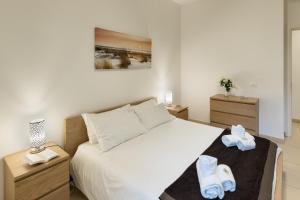 una camera da letto con letto, lenzuola bianche e pantofole di Casa Massima Suites a Casamassima