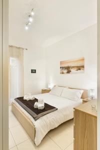 una camera bianca con un grande letto con asciugamani di Casa Massima Suites a Casamassima