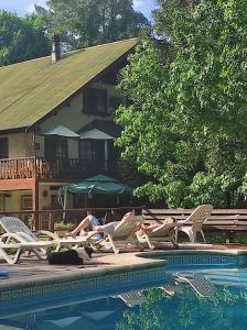 two people laying on lounge chairs next to a swimming pool at Alpenhaus Bier und Gasthaus in Tigre