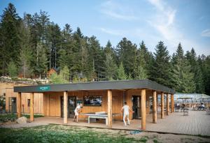 a building with a black roof with people standing on a deck at Huttopia Forêt des Vosges in Barbey-Séroux