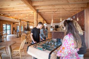 a group of people standing around a ping pong table at Huttopia Forêt des Vosges in Barbey-Séroux