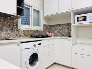 a white kitchen with a washing machine in it at New - Luxury Studio 3 Minutes From Beach ! in Tel Aviv