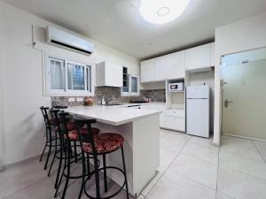 a kitchen with white cabinets and bar stools at New - Luxury Studio 3 Minutes From Beach ! in Tel Aviv