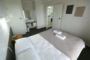 a bedroom with a bed with two towels on it at Maple Lodge Motel in Matamata