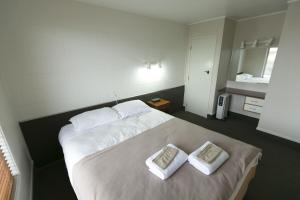 a bedroom with a large bed with two pillows on it at Maple Lodge Motel in Matamata