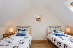 2 camas en una habitación con paredes blancas y almohadas azules en Honeysuckle Cottage at Williamscraig Holiday Cottages, en Linlithgow
