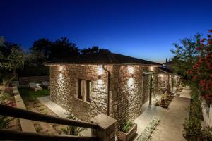 a stone house with lights on it at night at La Terra Petra in Skala Rachoniou