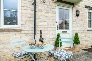 a table with a bottle of wine and two chairs at Oxfordshire Living - The Sunderland Apartment - Bladon in Bladon