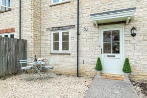 a table and chairs in front of a brick house at Oxfordshire Living - The Sunderland Apartment - Bladon in Bladon