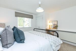 a white bed with blue pillows in a bedroom at Oxfordshire Living - The Sunderland Apartment - Bladon in Bladon