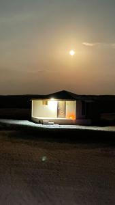 a small building at night with the moon in the sky at Safari Dunes Camp in Ḩawīyah