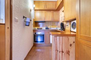 a kitchen with wooden cabinets and a sink and a stove at La Fusta in Saint-Lary-Soulan
