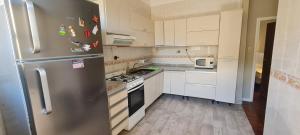 a kitchen with white cabinets and a stainless steel refrigerator at Alojamiento La Floresta, 3 ambientes para 5 personas in Buenos Aires