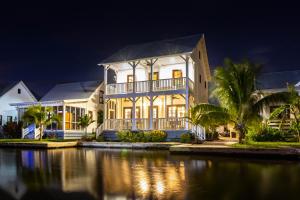 a large house at night with a body of water at Casa Blanca and The PoolClub at Mahogany Bay in San Pedro