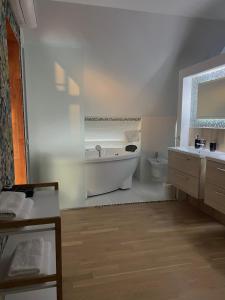 a white bathroom with a tub and a toilet at Boutique Guest House in Liepāja