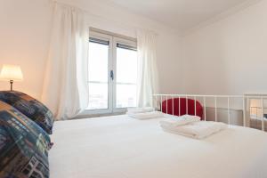 um quarto com uma grande cama branca e uma cadeira vermelha em FLH Expo Cozy Apartment em Lisboa