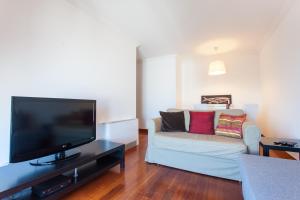 ein Wohnzimmer mit einem Sofa und einem Flachbild-TV in der Unterkunft FLH Expo Cozy Apartment in Lissabon