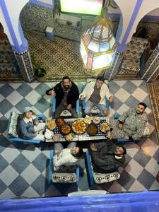 un gruppo di persone seduti intorno a un tavolo con cibo di Riad Mauritania a Chefchaouen