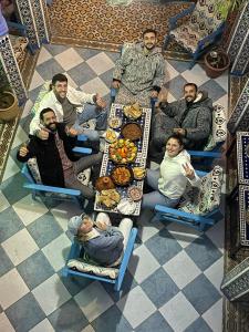 un gruppo di persone seduti intorno a un tavolo con cibo di Riad Mauritania a Chefchaouen