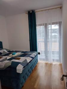 a bedroom with a bed and a large window at Helena apartman in Ocka Gora