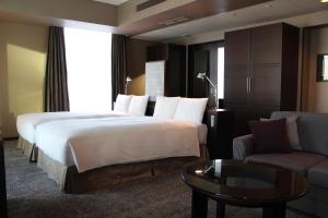 a hotel room with a large bed and a couch at The Royal Park Hotel Iconic Tokyo Shiodome in Tokyo