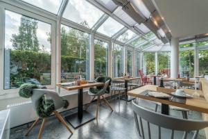 a restaurant with large windows and wooden tables and chairs at Auszeit Hotel Hamburg in Hamburg