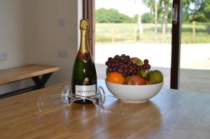 a bottle of wine and a bowl of fruit on a table at The Farmhouse at Williamscraig Holiday Cottages in Linlithgow