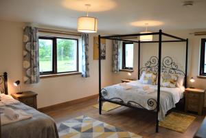 a bedroom with a canopy bed and two windows at The Farmhouse at Williamscraig Holiday Cottages in Linlithgow